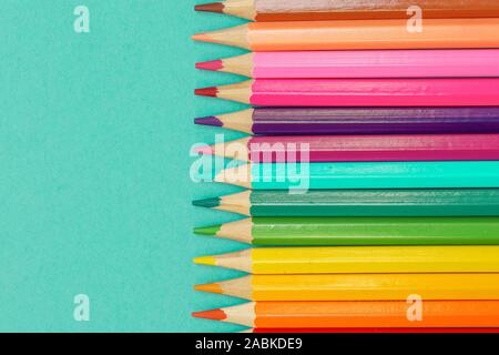 Close up row of colored pencils isolated against a blue background Stock Photo