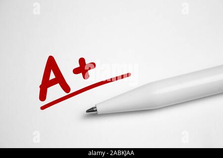 A plus A grade written in red pen on notebook paper. Stock Photo