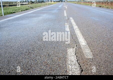 New road with cracked asphalt surface at country way. Deficient  execution of civil construction concept Stock Photo