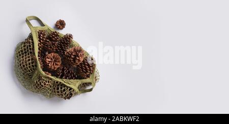 Christmas zero waste. Natural material for handmade DIY, pine cones in green cotton eco bag on grey. Eco friendly Xmas. View from above, flat lay styl Stock Photo