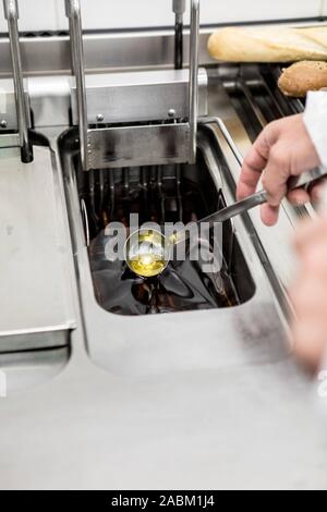 In a staged food inspection, fat is checked in the deep fryer. The ...