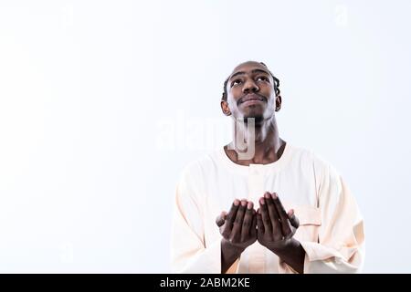 Handsome Young  African Muslim Man Making Traditional Fatiha Prayer To Allah God While Wearing A Traditional Sudan fashion clothes in studio Stock Photo