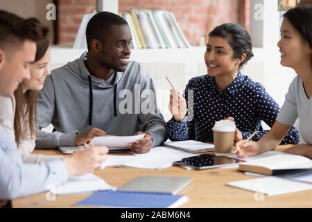 Happy diverse college friends listening to indian female teammate. Stock Photo