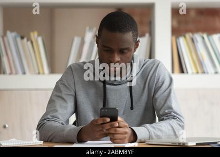 Focused black male student web surfing educational information online. Stock Photo