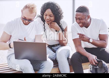 Beautiful multi ethnic friends using a laptop in the Street. Youth lifestyle concept Stock Photo