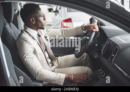 Stylish black businessman sitting behind the wheel of new luxury car. Rich african american man Stock Photo