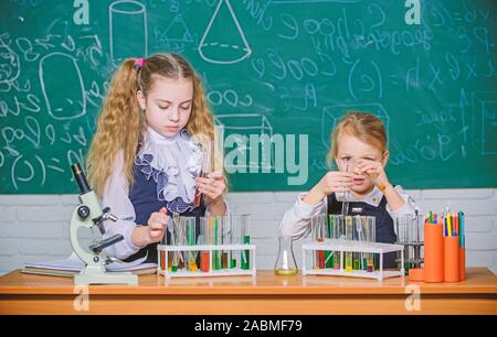 Improving their study skills. Study group in chemistry laboratory. Little school children holding test tubes during study session. Small schoolgirls performing study experiment in chemistry. Stock Photo