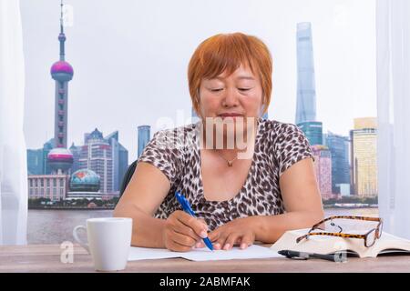Asian woman in the office writing on a paper with a pen Stock Photo
