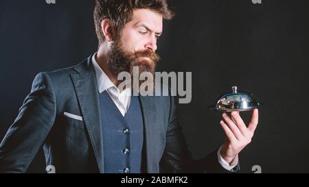 Elite luxurious. Secret under cloche. Exclusive food hidden cloche. Here is your meal. Something special. Man well groomed bearded gentleman formal suit hold little cloche. Serving and presentation. Stock Photo