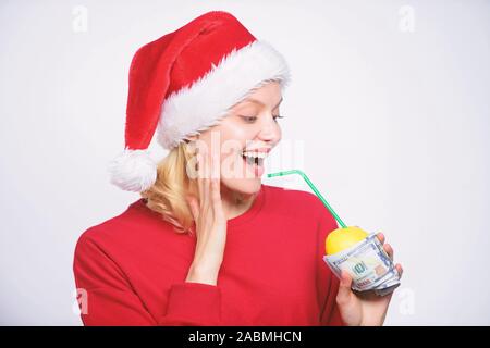 Girl santa hat drink juice lemon wrapped in banknote. Totally natural lemon juice. Fresh lemonade drink with straw. Symbol of wealth and richness. Girl with lemon and money. Lemon money concept. Stock Photo