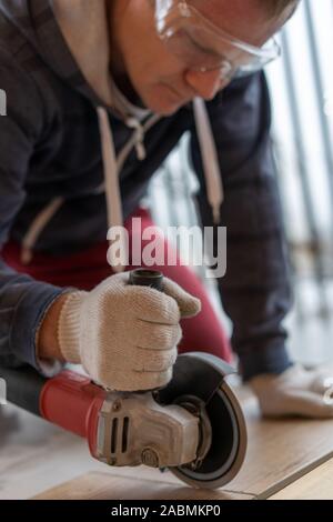 repair and decoration. a man cuts ceramic tiles with a grinder. Stock Photo
