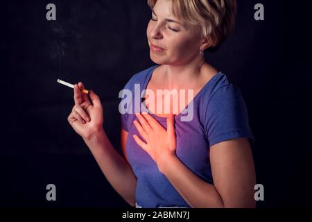 Woman smokes cigarette and has problem with lungs or heart attack. Nicotine addiction concept Stock Photo