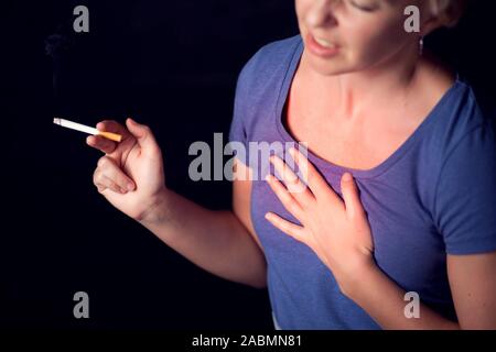 Woman smokes cigarette and has problem with lungs or heart attack. Nicotine addiction concept Stock Photo