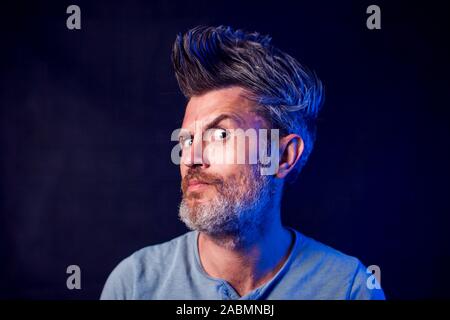 A portrait of bearded man with surprised face in front of black background Stock Photo
