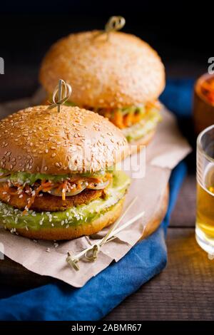 Vegan sweet potato chickpea burgers with avocado guacamole sauce and carrot slaw on dark blue background close-up.Vegetarian healthy snack,plant based Stock Photo