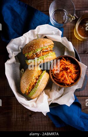 Vegan sweet potato chickpea burgers with avocado guacamole sauce and carrot slaw on wooden background top view.Vegetarian meal,plant based food Stock Photo
