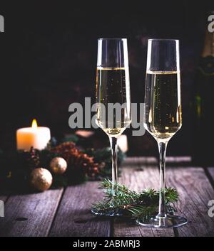 Two glasses of champagne with holiday decorations in background on a rustic wooden table Stock Photo