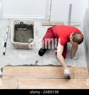 repair and decoration. the tiler puts the porcelain tiles on the floor in the apartment Stock Photo