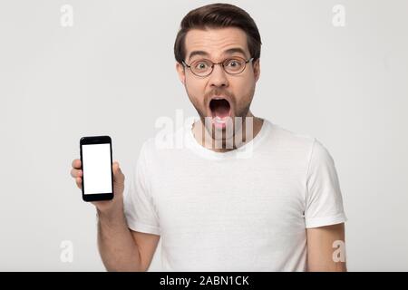 Amazed millennial guy in glasses show cellphone screen Stock Photo