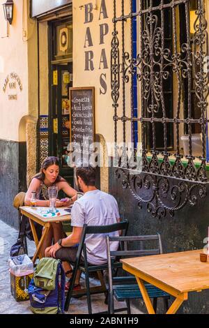 People enjoying outdoor sidewalk cafes in Santa Cruz or old Jewish Quarter of Seville Andulsia Spain