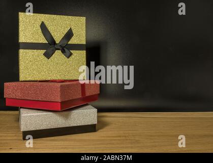 three gift boxes in red silver and gold on black background Stock Photo