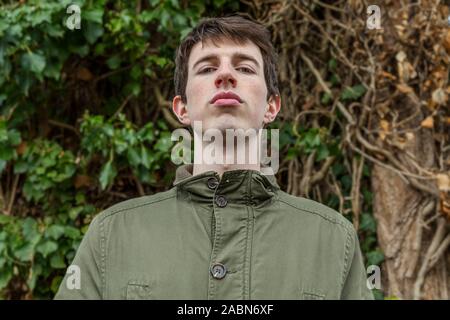 A young man in his late teens or early twenties looks down confidently toward the camera in a position of power or dominance. Stock Photo