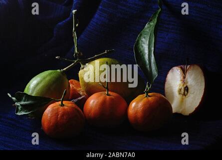 Lemon and tamiringe fruits with an half apple on a dark blue background Stock Photo