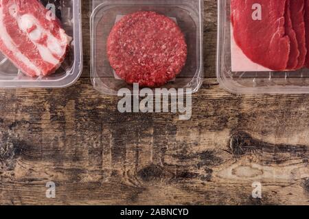Different types of meat packaged in plastic on wooden table. Top view. Copy space Stock Photo