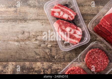Different types of meat packaged in plastic on wooden table. Top view. Copy space Stock Photo