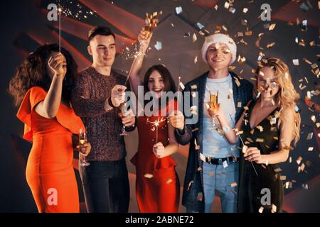 A group of friends are having fun in beautiful chiffon dresses with champagne and confetti, preparing for the New Year Stock Photo