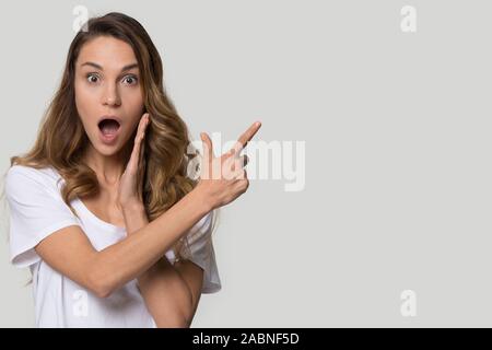 Surprised excited young woman pointing finger at copy space Stock Photo
