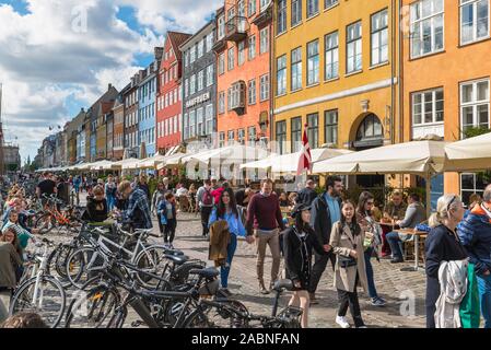 Copenhagen Denmark, view of tourists strolling along the cafe lined quayside in the colorful Nyhavn harbor area of Copenhagen, Denmark. Stock Photo