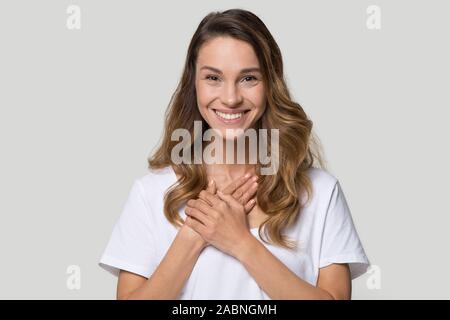 Head shot portrait grateful young woman holding hands on chest Stock Photo
