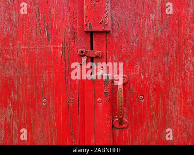 Old red door in ancient traditional stone barn in farmyard in Eden Valley, Cumbria, England, UK Stock Photo