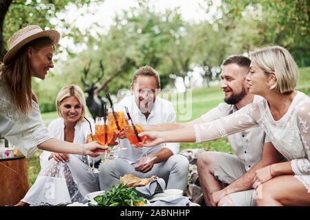 Having nice time. Group of adult friends have a rest and conversation in the backyard of restauraunt at dinner time Stock Photo