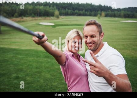 A pair of golfers make a photo on the golf course using a stick like a sephi pole Stock Photo