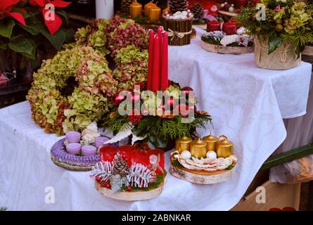 Various Christmas wreaths and centre table of flowers and candles for sale on a Market table Stock Photo