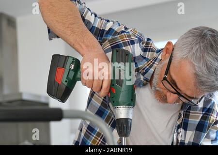 Mature man using power drill at home Stock Photo