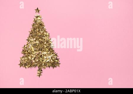 Christmas tree made of golden stars glitter confetti on pink background. Xmas holiday backdrop. Greeting card. View from above, flat lay style. Space Stock Photo