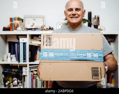 Paris, France - Jul 10, 2019: Front view of happy senior man holding Amazon Day Prime cardboard during annual shopping event organized by the e-commerce giant Stock Photo