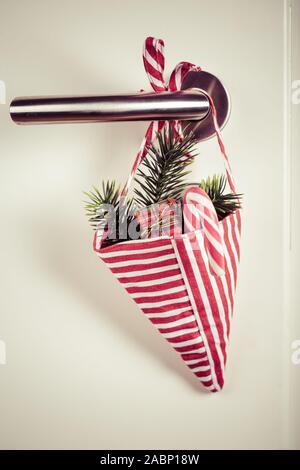 Small Christmas bag with branch and candy cane hanging on door handle in vintage style Stock Photo