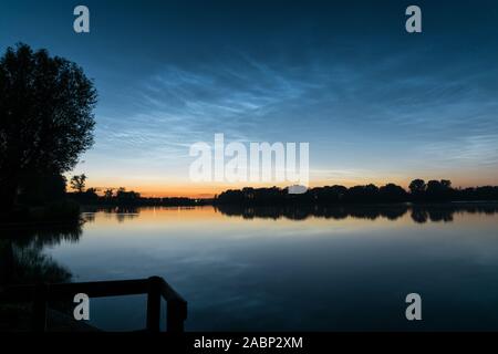 Scenic view of noctilucent clouds (NLC, shining night clouds) over a lake in Holland around midnight Stock Photo