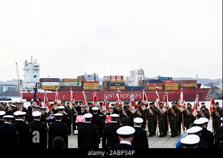 Container ship arrives at the port during the 101st anniversary of the creation of the Polish Navy.During the ceremony for the first time war flag of an ORP Slazak ship was raised. ORP Slazak is a Polish patrol corvette class ship. The unit is a part of the Battle Ship Squadron of the 3rd Ship Flotilla. The ship's purpose is to combat surface and aerial targets and asymmetrical threats, as well as patrol and protect approach routes and sea communication lines, escort and protect commercial units. The unit is also adapted to control sea routes as part of multinational forces, combat piracy and Stock Photo