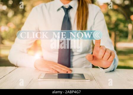 Handwriting text Click Me Now. Conceptual photo Internet helping desk Press the button Online Icon Nertwork Female business person sitting by table an Stock Photo