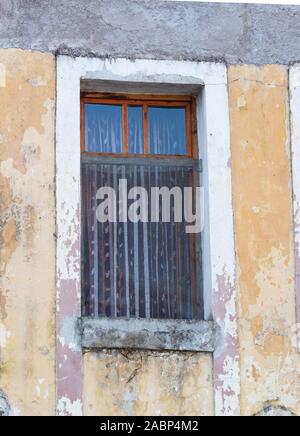 Gjirokaster, Albania - September 26, 2019: Open window with sheer curtains in a stucco building in a state of disrepair. Photographed in Albania. Stock Photo