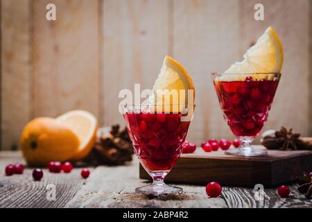 Two vintage glasses of mulled wine with cranberries, orange slices and star anise on rustic wooden table, close up Stock Photo