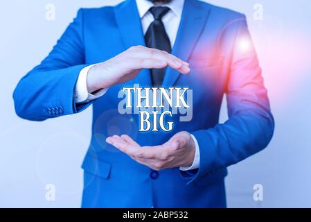 Conceptual hand writing showing Think Big. Concept meaning To plan for something high value for ones self or for preparation Man in front of table. Mo Stock Photo