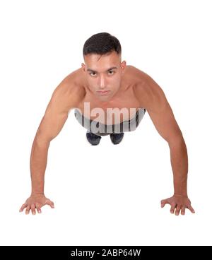 A young east Indian man doing his push aps on the floor in the studio looking into the camera, isolated for white background Stock Photo