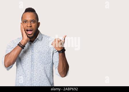 Amazed African American man pointing finger at copy space isolated Stock Photo