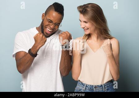 Happy African American man and Caucasian woman celebrating success Stock Photo